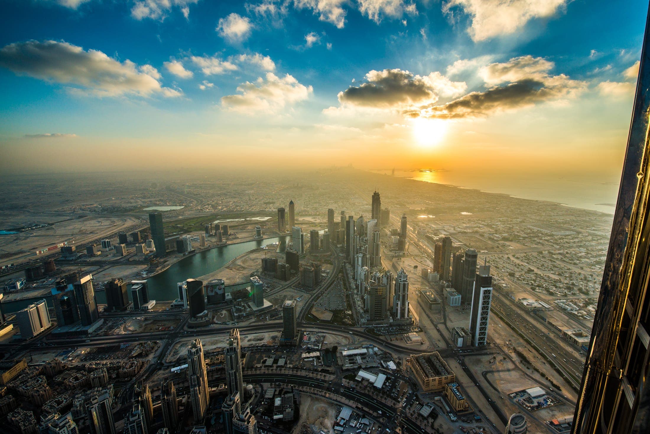 Dubai skyline at golden hour sunset, viewed from Burj Khalifa with Downtown Dubai towers below